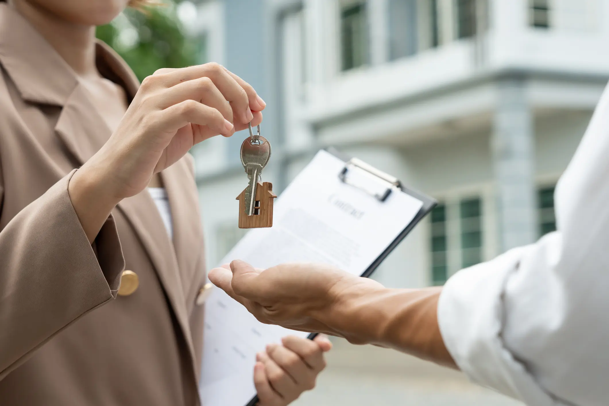 A person handing over a house key during a real estate transaction.