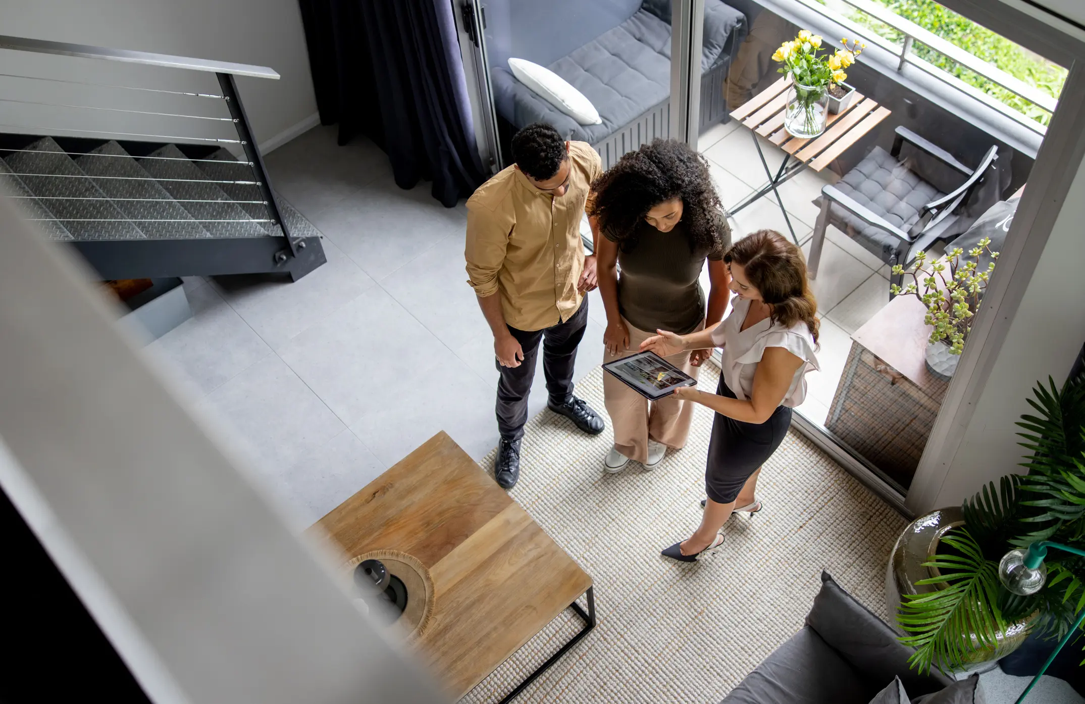 Three people discussing plans around a table in a modern room.