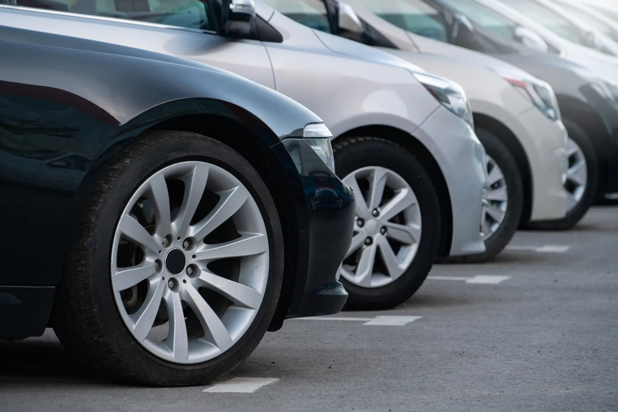 Close-up of parked car wheels in a row.