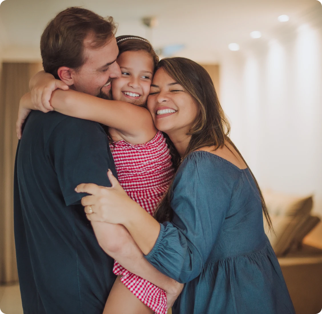 Family group hug with smiles indoors.