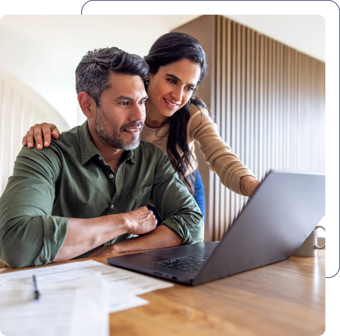 Couple using laptop at wooden table.